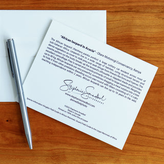 Back view of an African leopard wildlife notecard showing species description lying flat on a table with a pen and envelope