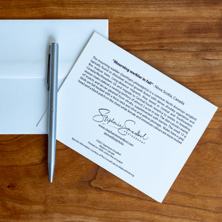 Back view of a mourning warbler wildlife notecard showing species description lying flat on a table with a pen and envelope